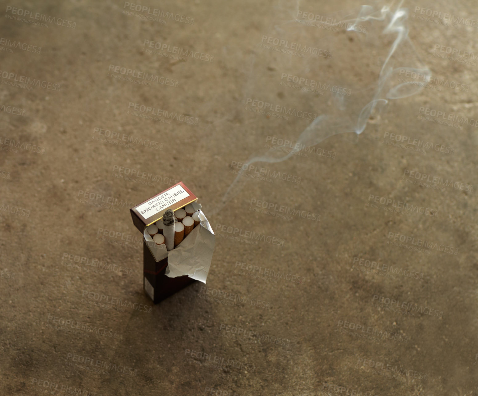Buy stock photo Closeup shot of an open box of cigarettes with one burning, and smoke drifting