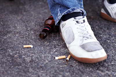 Buy stock photo Feet, cigarettes and beer in a road in the city for a man with sneakers smoking and drinking. Shoes, addiction and closeup of tobacco and an alcohol bottle in the outdoor street of an urban town.