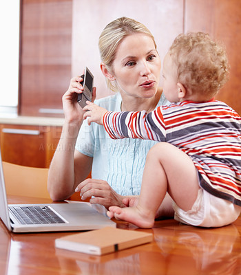 Buy stock photo A mother and her baby playing around with a cellphone and computer