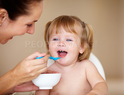 Buy stock photo A cute little girl being fed by her mother