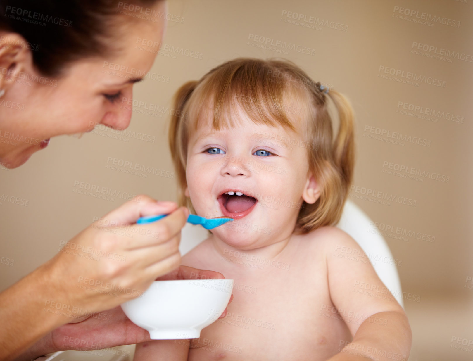 Buy stock photo A cute little girl being fed by her mother