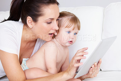 Buy stock photo A cute little girl and her mother looking at a digital tablet together