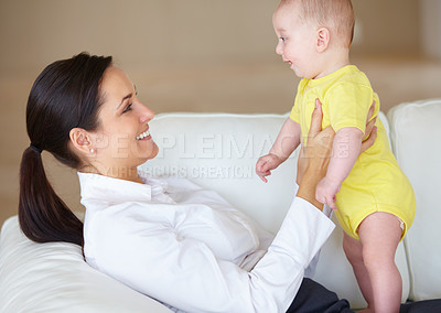 Buy stock photo Beautiful young mother playing with her baby on her couch