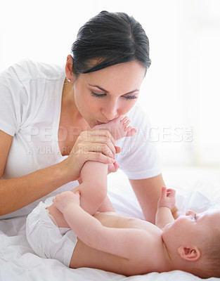 Buy stock photo Beautiful woman kissing her baby's feet
