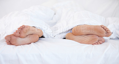 Buy stock photo Cropped image of the feet of two people in bed facing in two different directions