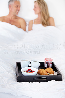 Buy stock photo Happy couple, bed and breakfast for morning, wakeup or room service in romance at hotel suite. Man and woman smile with food, meal or snack tray in bedroom of jam jar croissant, coffee or fruit salad