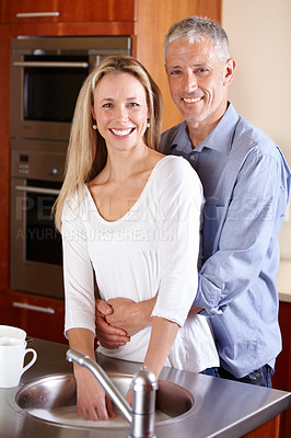 Buy stock photo A happy couple in their kitchen smiling at the camera