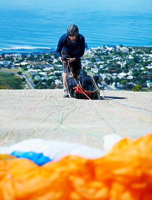 Buy stock photo Man, parachute and paragliding sport in launch on hill, healthy adventure and extreme fitness by ocean. Person, preparation and fearless by bench for flight with helmet and safety gear by blue sky