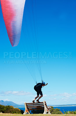 Buy stock photo Man, parachute or paragliding sport in launch exercise, healthy adventure or extreme fitness for wellness. Person, preparation and fearless by bench for flight with helmet and safety gear by blue sky