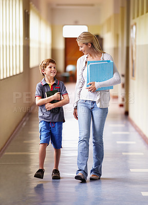 Buy stock photo A teacher and young boy walking together down the corridor
