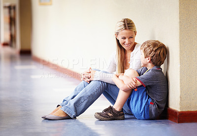 Buy stock photo A teacher sitting with a student in the hallway talking