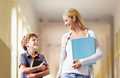 Buy stock photo Talking, teacher and boy walking, hallway and happiness with advice, help and education. Male child, student and woman with a smile, lobby and conversation with joy, communication and development