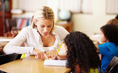 Buy stock photo Teacher, teaching and child learning to write at school for education, knowledge or development. Woman with girl student for solution, notebook and pencil at a classroom desk with support and help