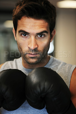 Buy stock photo Portrait of a focused man wearing boxing gloves and sport clothing posing ready to fight