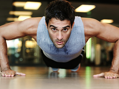 Buy stock photo Portrait of a handsome man wearing sports clothing doing pushups at the gym