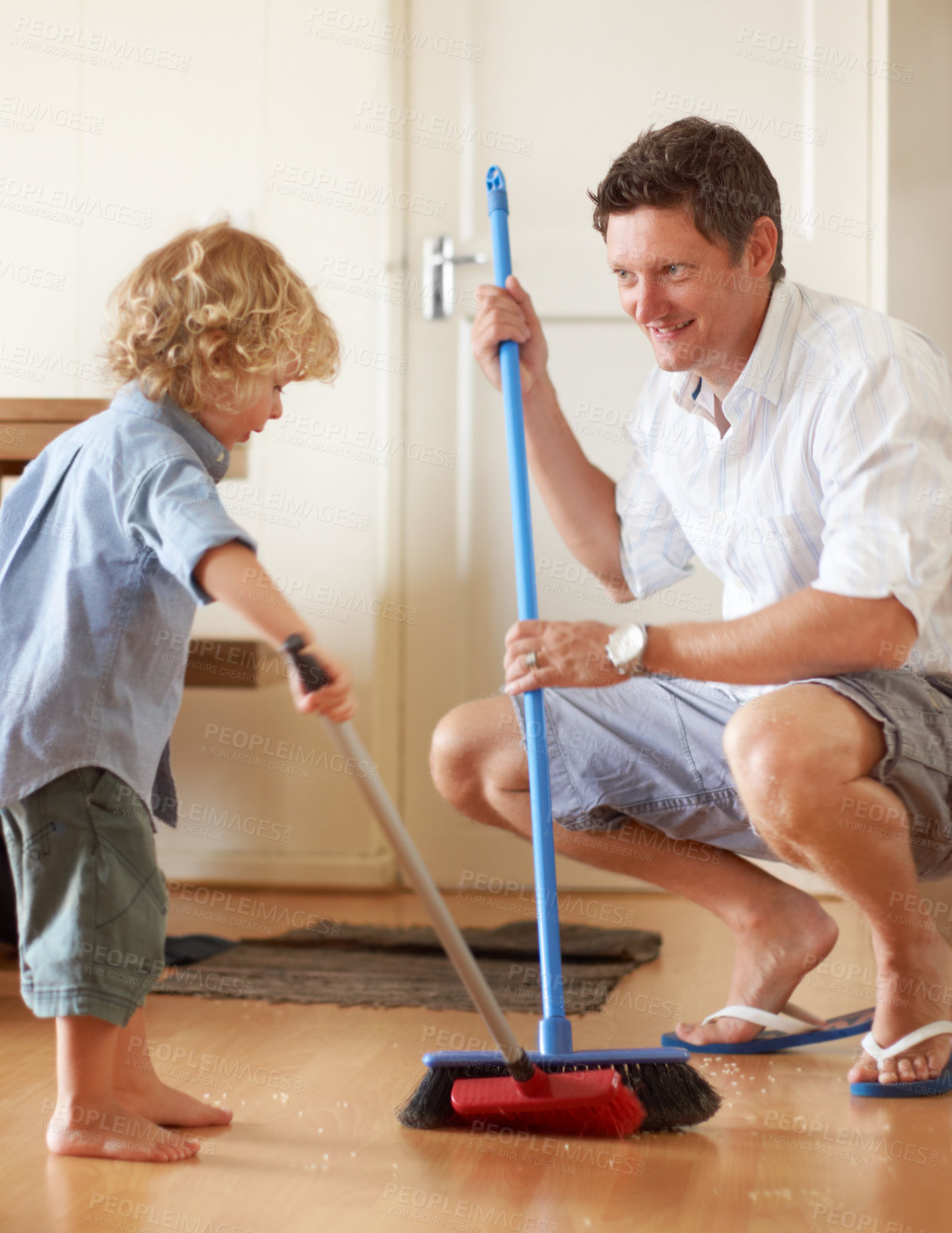 Buy stock photo A father and toddler son sweeping up sand together in their home