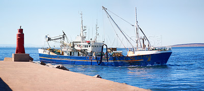 Buy stock photo Shot of a fishing trawler leaving the harbour