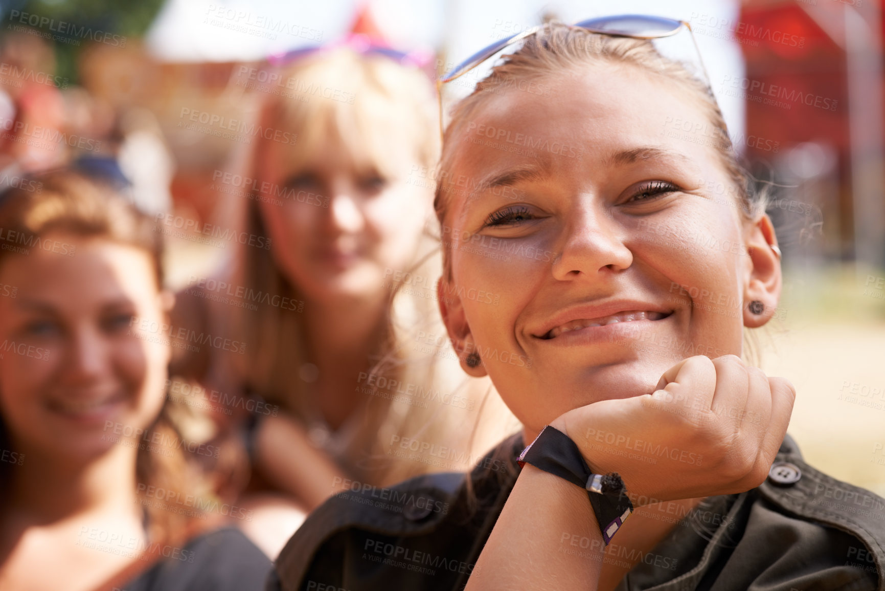 Buy stock photo portrait of happy young woman smiling with chin rested on her hand and friends sitting in the background