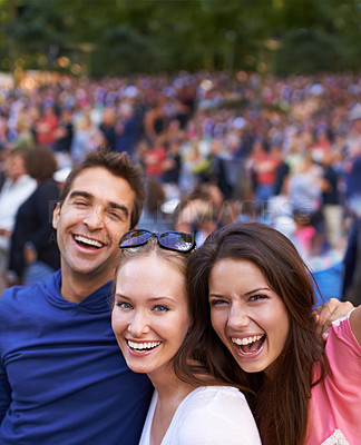 Buy stock photo A group of smiling friends standing together at a music festival with crowd in the background