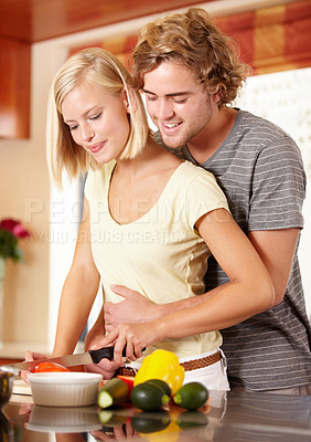 Buy stock photo A happy young couple cooking in the kitchen