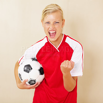 Buy stock photo Shot of a young woman dressed in a soccer uniform celebrating and holding a soccer ball