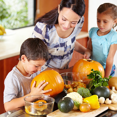 Buy stock photo Shot of a mother helping her children carve pumpkins for halloween
