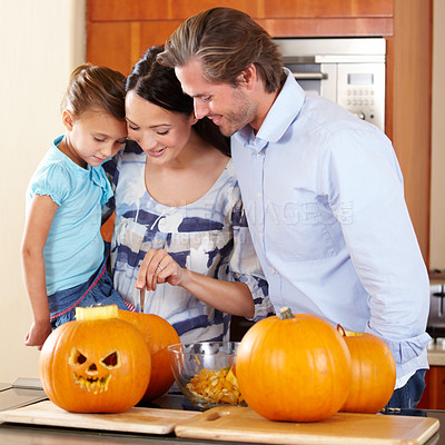 Buy stock photo Halloween, pumpkin and a family in the kitchen of their house together for holiday celebration. Creative, smile or happy with a mom, dad and daughter carving a face into a vegetable for decoration