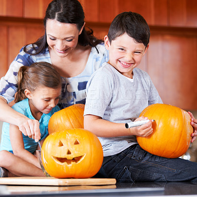 Buy stock photo Halloween, pumpkin and a family in the kitchen of their home together for holiday celebration. Creative, smile or happy with a mother, son and daughter carving a face into a vegetable for decoration