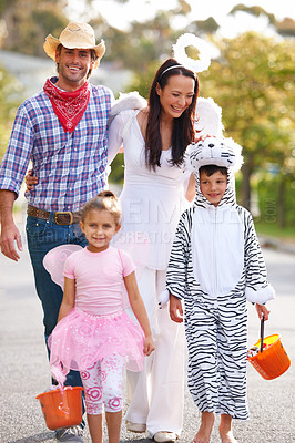 Buy stock photo Halloween, celebration and happy family walking in a street with love, smile and excited for vacation tradition. Costume, support and children with parents in a road for neighborhood candy collection