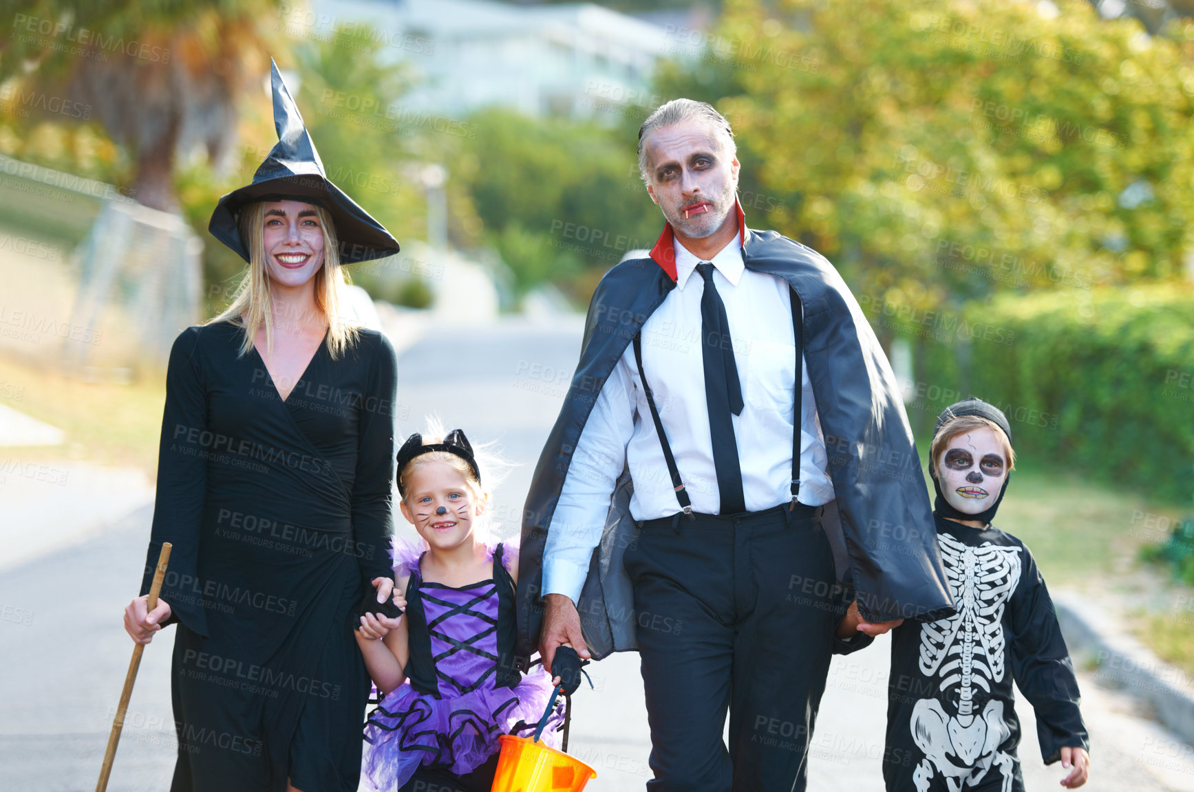 Buy stock photo A cute family dressed up for Hallowe'en walking down their street