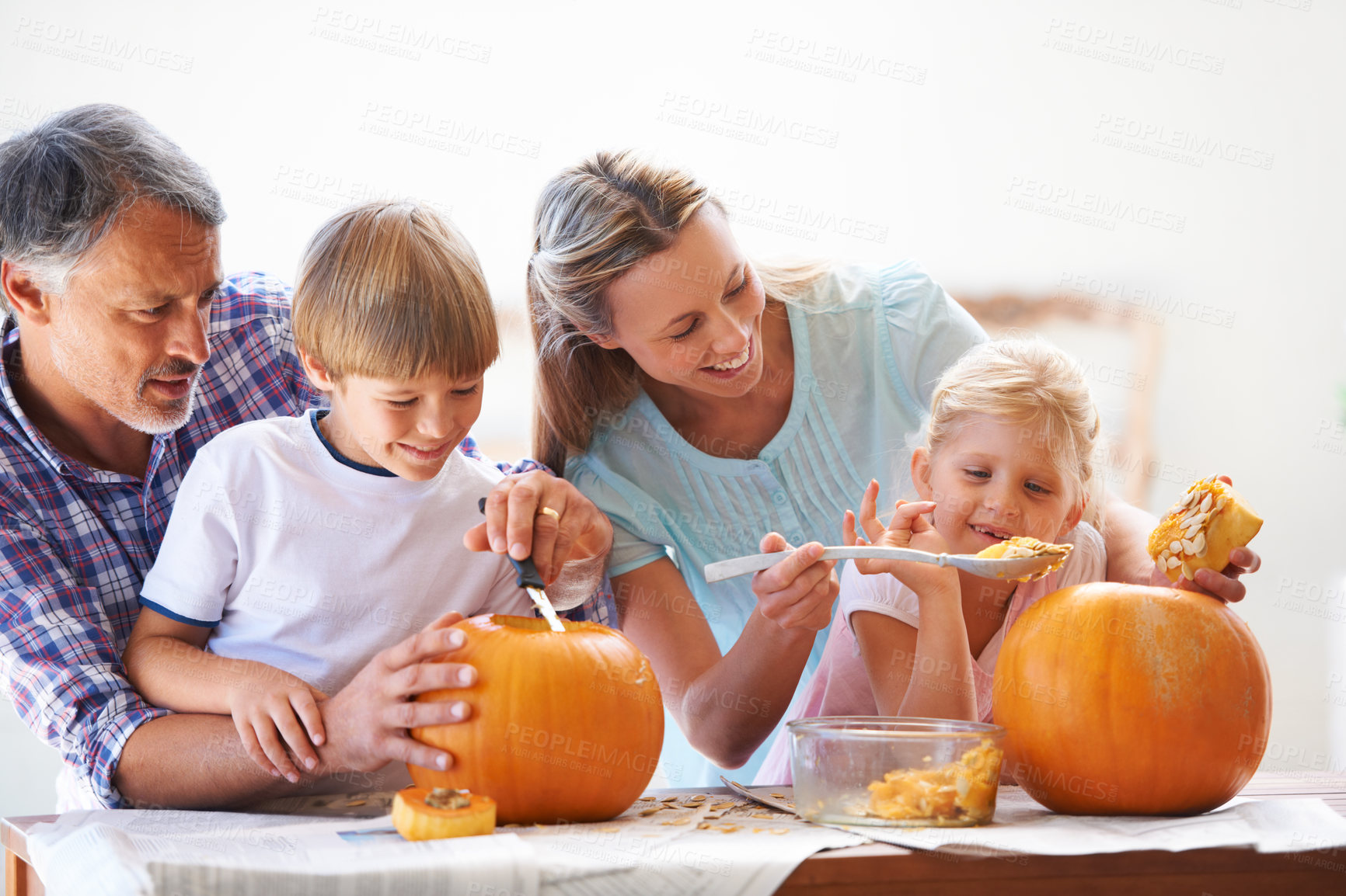 Buy stock photo Family, halloween and carving a pumpkin with children in a home for fun and bonding. Man and woman or parents and young kids together for creativity, holiday lantern and happy craft at a table