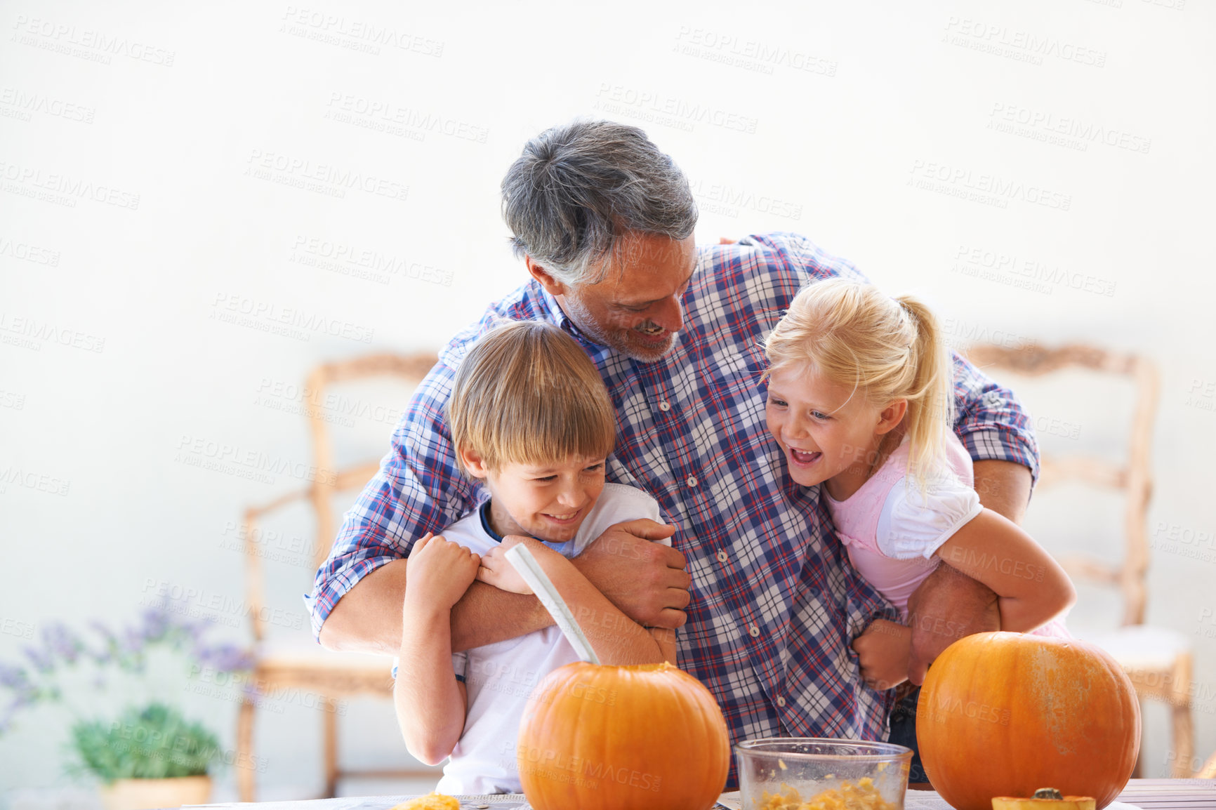 Buy stock photo Happy family, hug and halloween pumpkins for holiday decoration, childhood memories and joy. Father, children and embrace together with excitement, celebration and carving vegetable for tradition