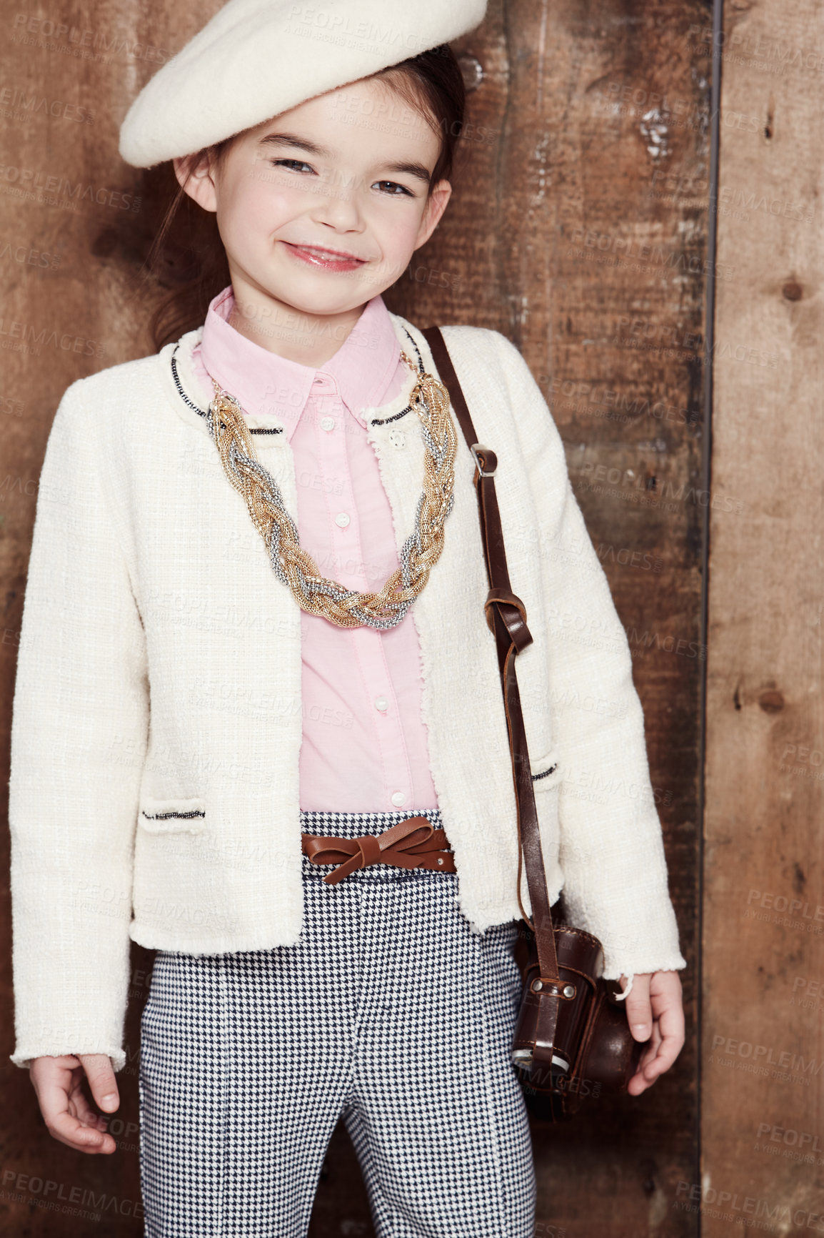 Buy stock photo Vintage, girl and portrait of child with fashion, style and happy in clothes on wood background or studio. Kid, smile and confidence in retro aesthetic or costume with hat, jewellery and bag 