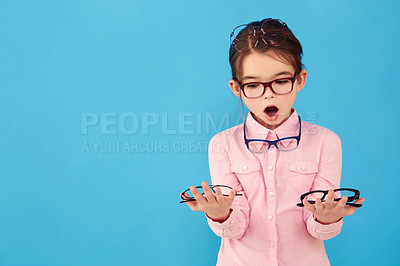 Buy stock photo Surprise, mockup and child with glasses choice for vision or eye care promotion isolated in a blue studio background. Wow, decision and young girl shocked by sale, discount and deal for eyewear
