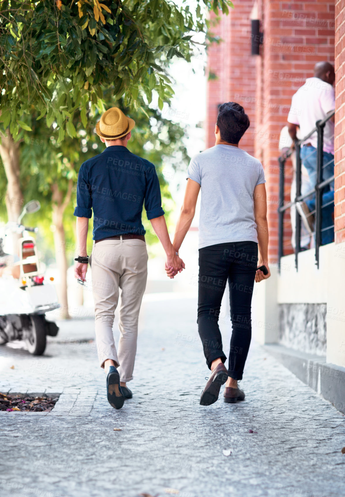 Buy stock photo Shot of a young gay couple waling outdoors while holding hands