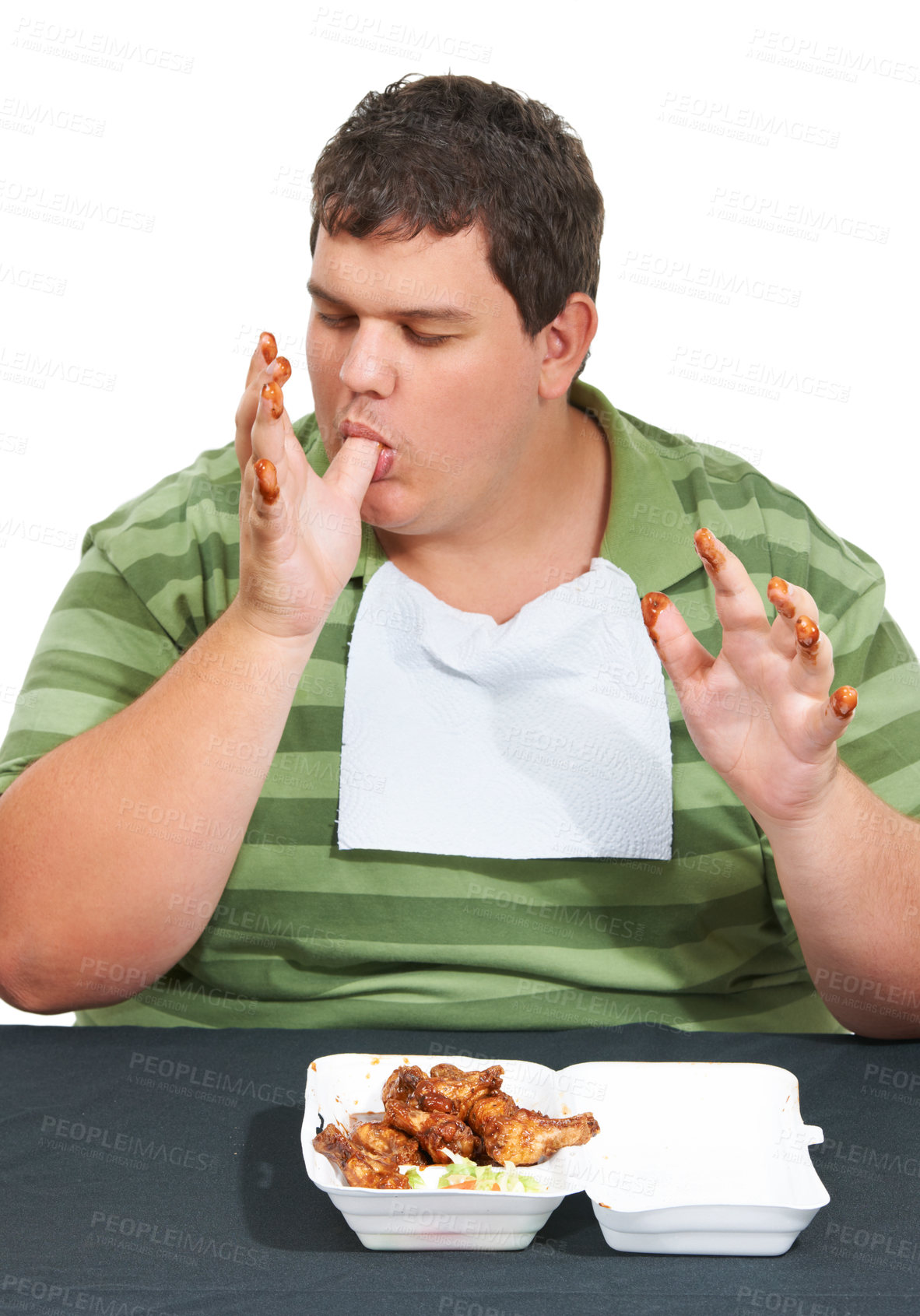 Buy stock photo Plus sized, eating and man with junk food, unhealthy diet and hungry person isolated on white background. Chicken, weight loss and food addiction problem, male model licking finger at table in studio