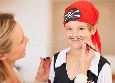 Buy stock photo Portrait of a smiling boy standing infront of his mother who is painting a mustache on his face