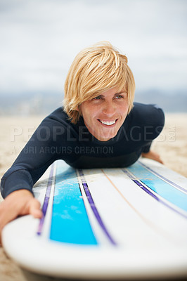 Buy stock photo Cropped shot of a female surfer lying on her surfboard