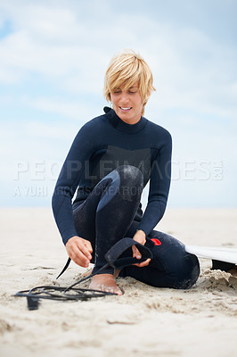 Buy stock photo Summer, beach and a man surfer getting ready in a wetsuit on sand by the coast for fitness, sports or recreation. Smile, nature and sky with a happy young athlete outdoor to prepare for surfing
