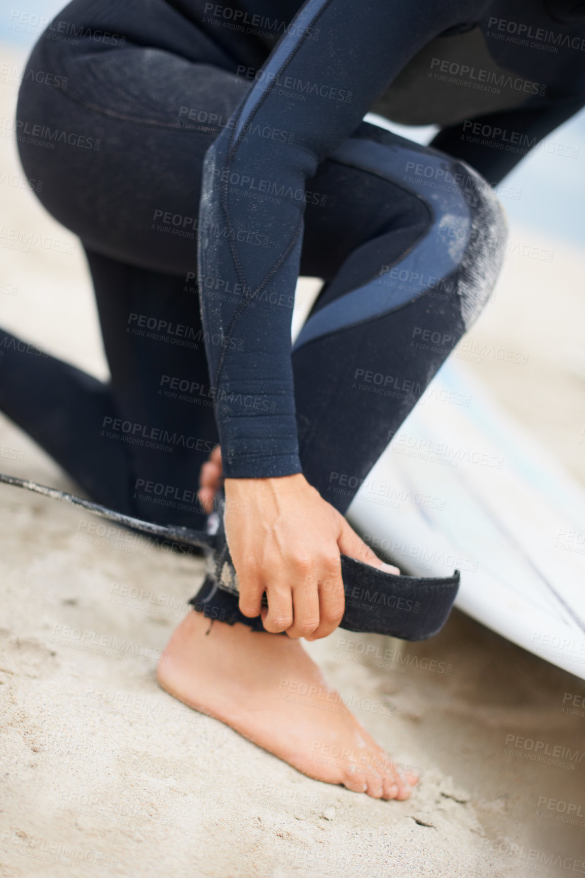 Buy stock photo Foot, ankle and strap with a surfer on the beach closeup, getting ready for sports or fitness training. Hands, hobby and tie with a person on the sand at the coast for safety during an exercise hobby