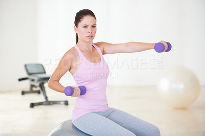 Buy stock photo Portrait of a young woman sitting on an exercise ball and doing some strengthening exercises with dumbbells