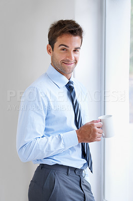 Buy stock photo Portrait, smile and coffee with a business man by a window in the office at the start of his work day. Corporate, company and career with a happy young employee drinking tea in the workplace