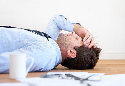 Buy stock photo A businessman lying on the floor with hand rested on his head and paperwork lying on the floor in front of him