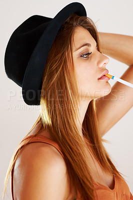 Buy stock photo Fashion, cigarette and woman smoking in studio with style, attitude or edgy aesthetic. Smoke, profile and female model smoker pose with cool, confidence and trendy outfit with bad habit or addiction