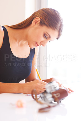 Buy stock photo Woman, writing or photographer by retro camera on table, thought or communication for courier envelope in home. Young person, message or notepad for idea, paper or send letter to post office in house