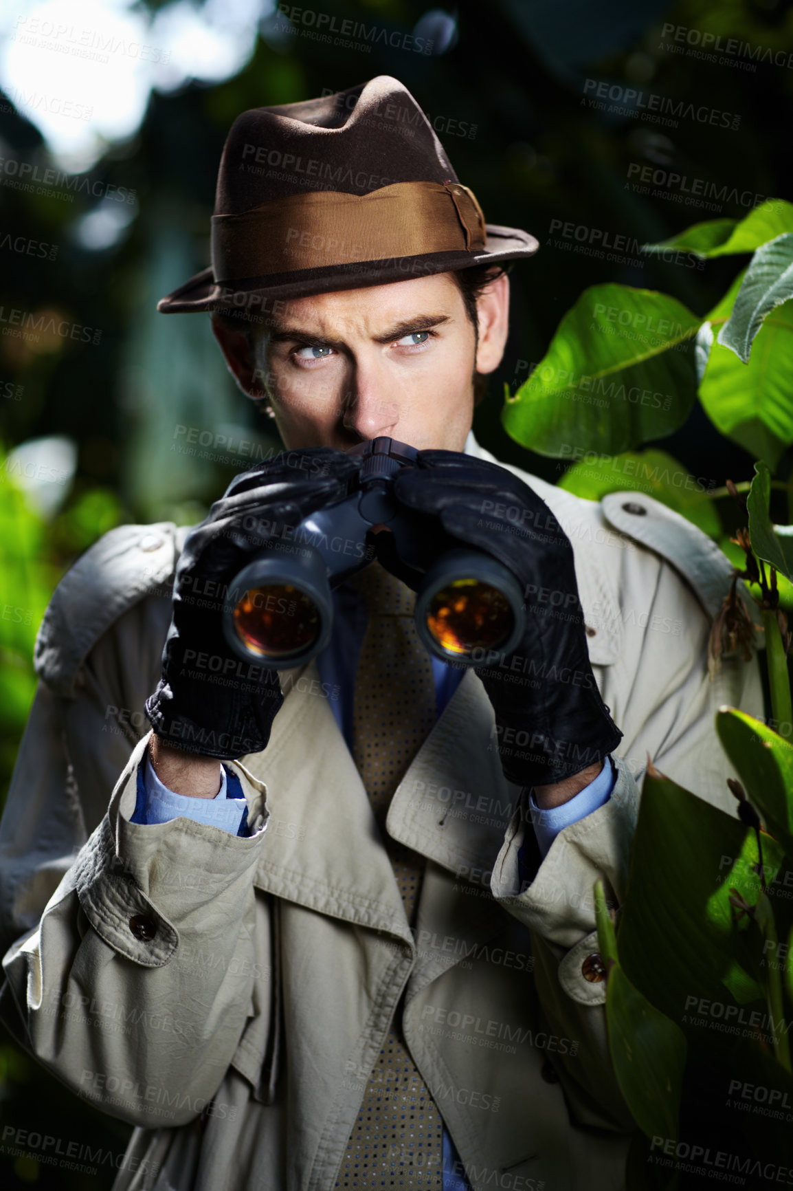 Buy stock photo Private investigator using binoculars to spy on someone from the bushes