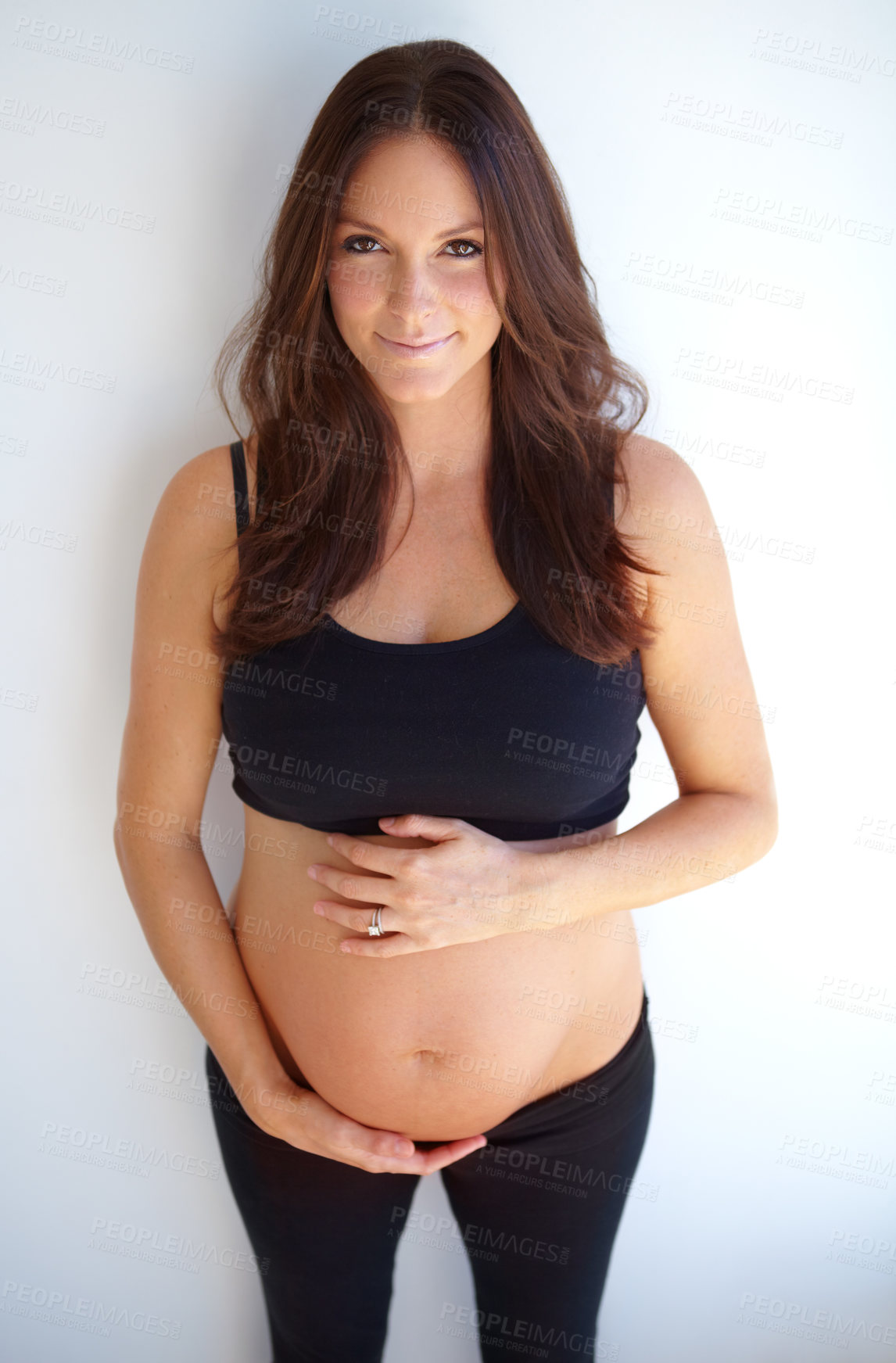 Buy stock photo Expectant mother holding her pregnant belly with a smile
