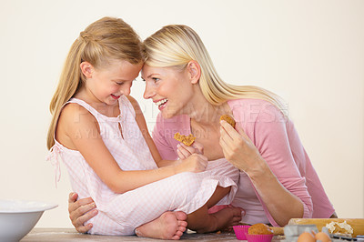 Buy stock photo A mother and daughter eating muffins after baking and bonding