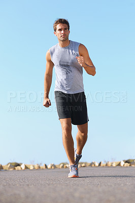 Buy stock photo Handsome young man jogging down the road - full length