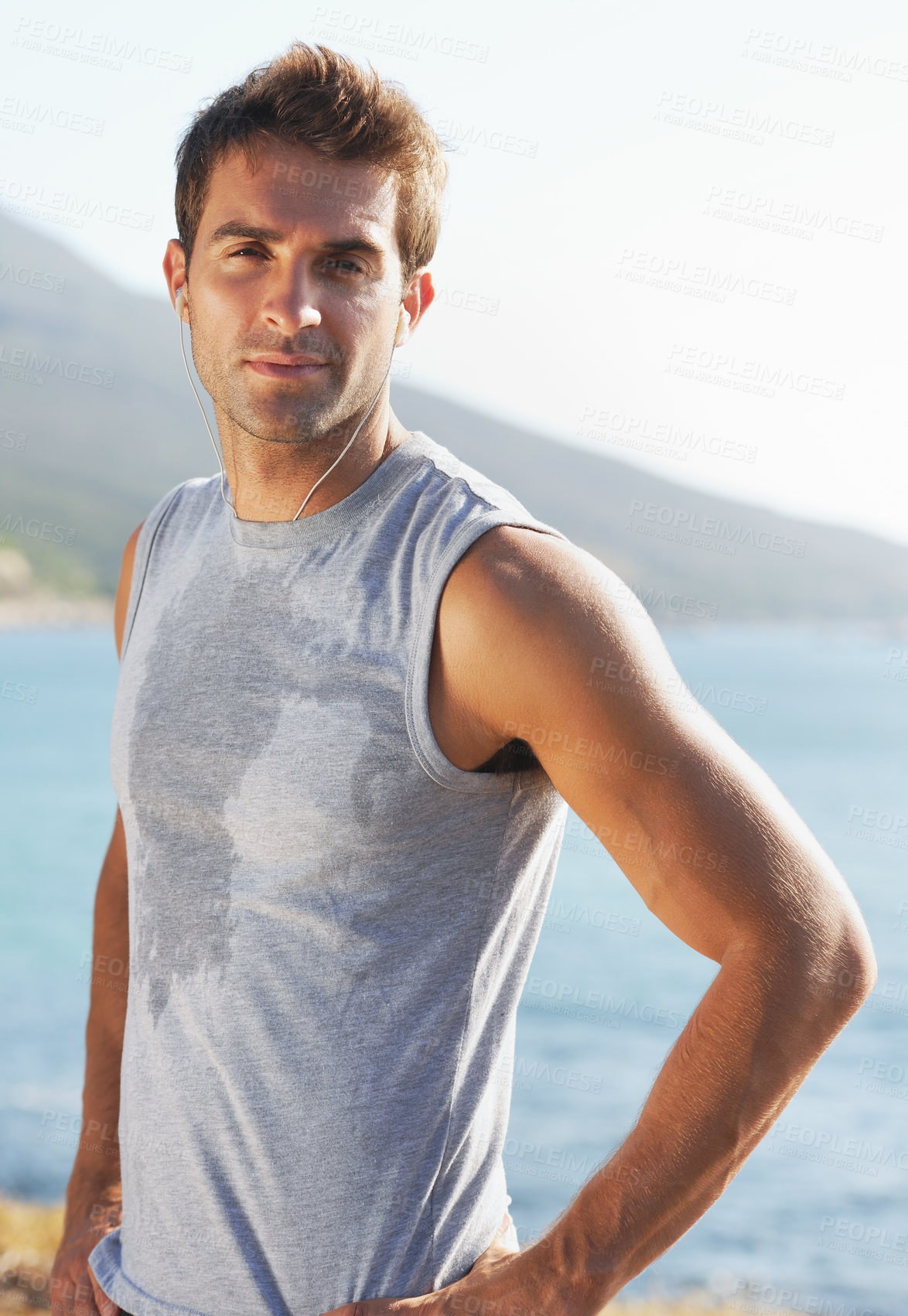 Buy stock photo Sports, portrait and man athlete running with sweat on road for exercise, cardio or outdoor training. Active, fitness and young male person with smile and earphones for music, playlist or album.